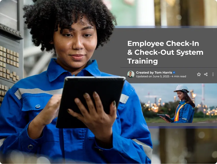 A woman in blue work overalls uses a tablet in a factory setting.
