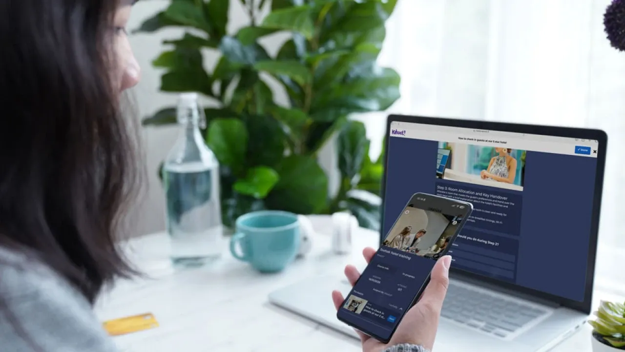 Woman following a Kahoot training course simultaneously on a laptop and smartphone