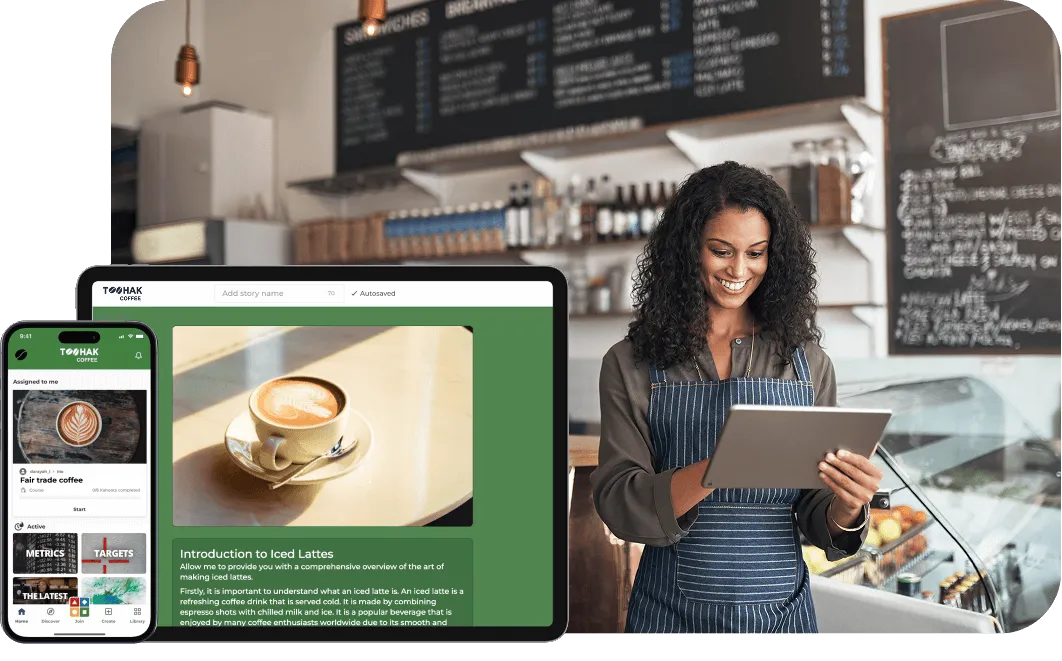 Smiling woman in a striped apron using a tablet behind the counter of a coffee shop, with menus visible on chalkboards in the background.