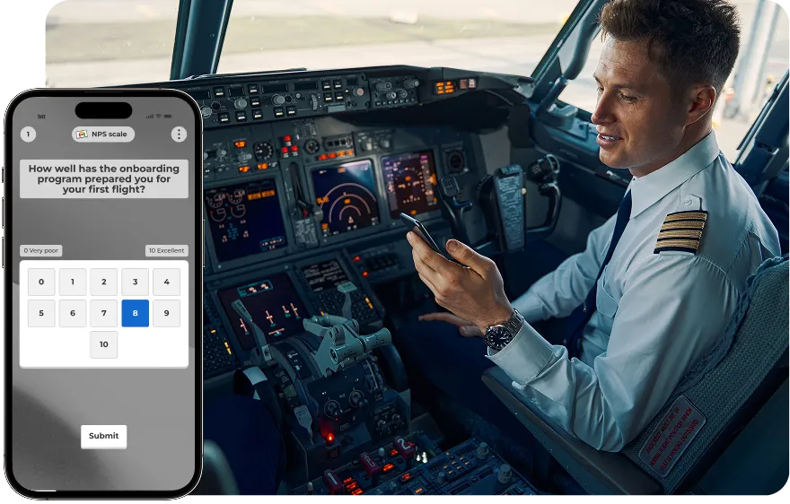 A smiling male pilot, wearing his uniform, sitting in the cockpit of an airplane and looking at his smartphone.