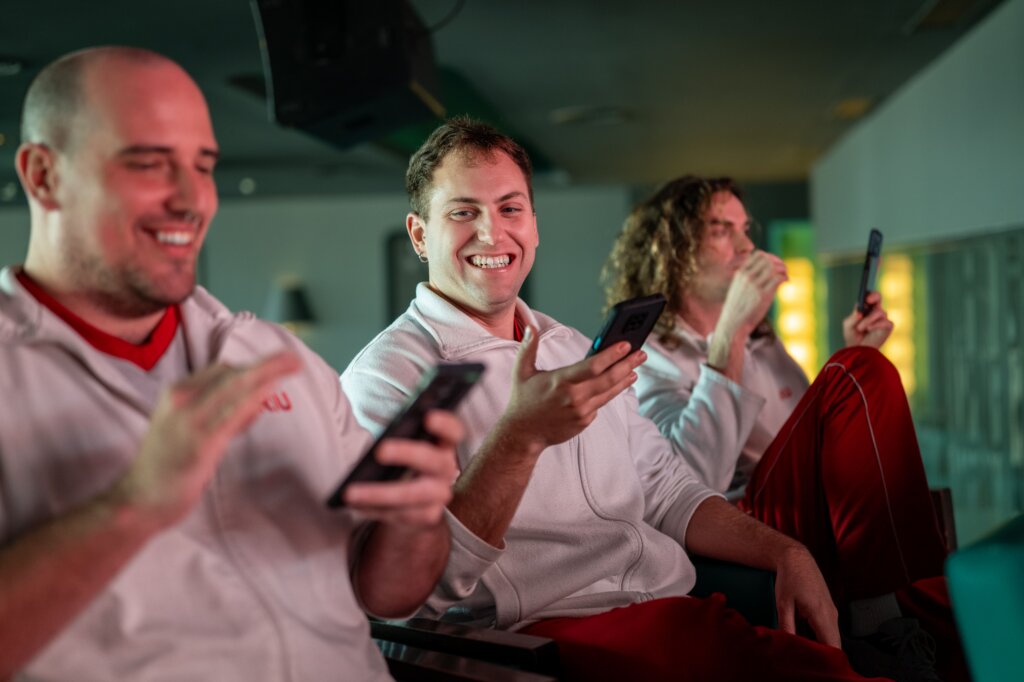 Three men are smiling playing Kahoot! During their staff training.