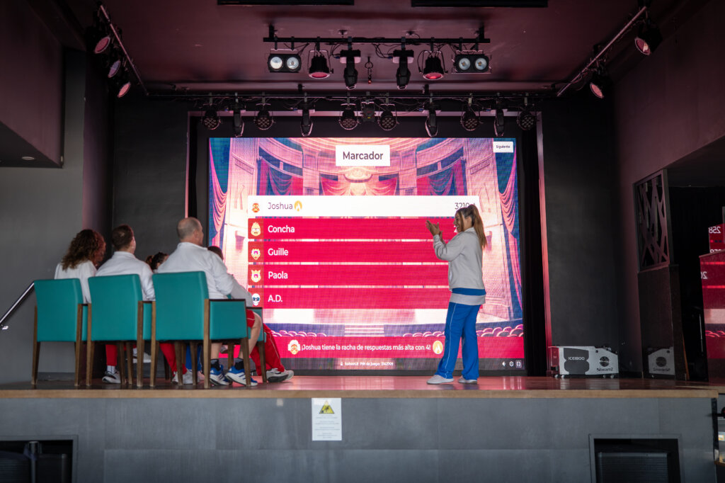 RIU Hotels & Resorts staff training A group of RIU entertainers is being trained using Kahoot! They are in uniforms sitting on a stage in front of a big screen.