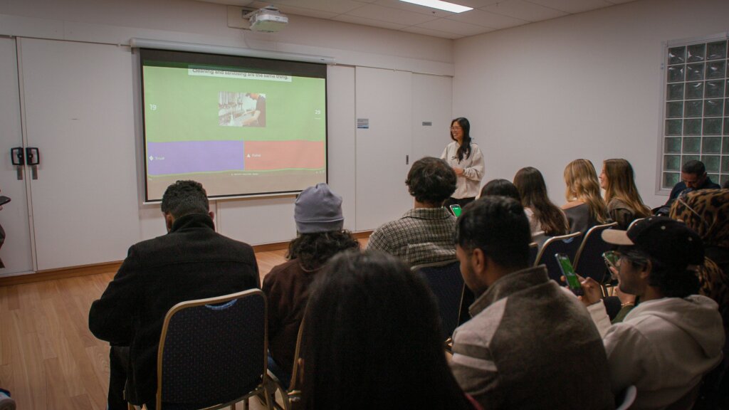 Trainer at El Jannah during Welcome Night using Kahoot! 360 on a big screen while the workforce learn and listen