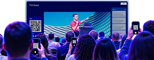 Conference audience scanning QR codes on their phones to join a Kahoot session with a live Q&A sidebar visible on the presentation screen